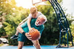 Older male adult and child on basketball court having fun