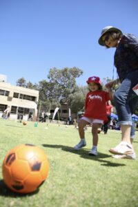 Child concentrating on an activity while an adult encourages nearby