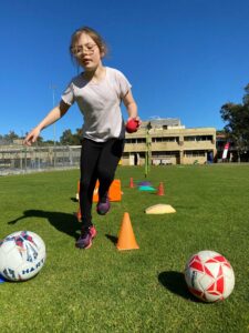 Young dribbling a ball outdoors, mid-movement