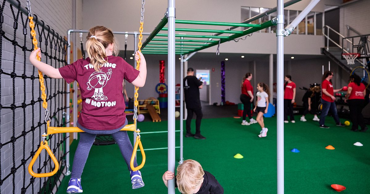 A child on a swing looking out over the main exercise floor at Thriving HQ in Balcatta