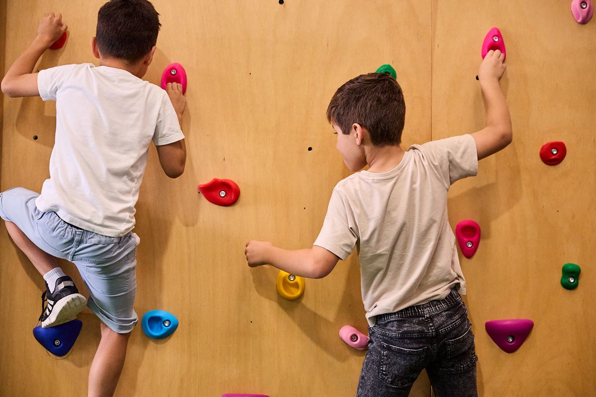 Two boys climbing the bouldering wall at Thriving HQ in Balcatta
