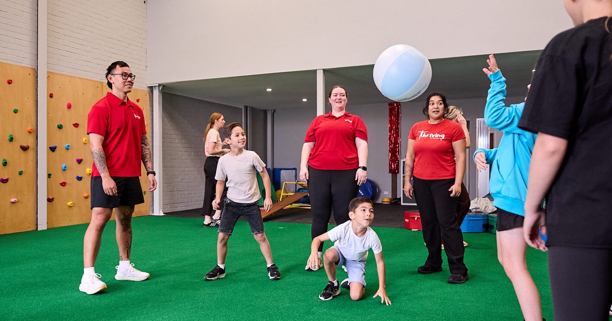 Children and Thriving staff playing a group ball game in the open exercise space at Thriving HQ
