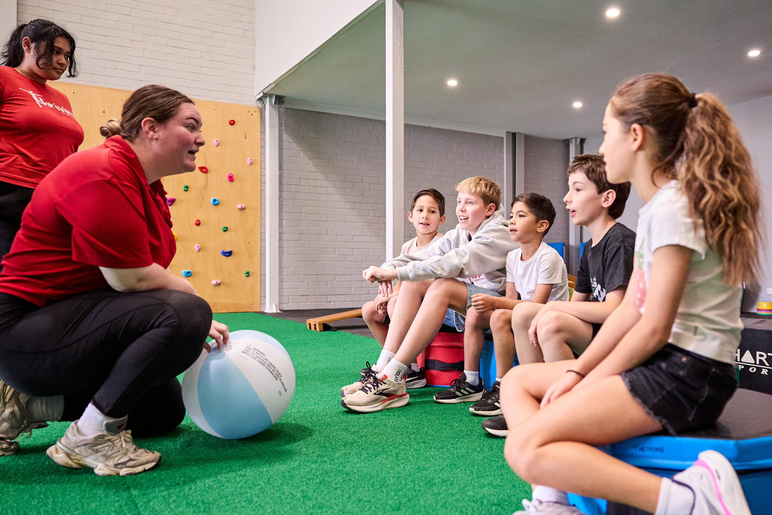 A staff member crouching to talk with a small group of older children.